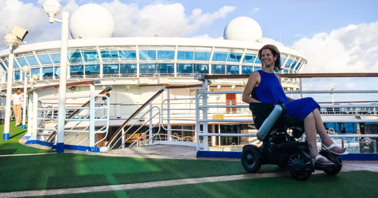 A person in a wheelchair on a Carnival Cruise ship, with an ocean view in the background.